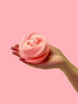 Peach background with a hand coming from the side holding a peach coloured sensory putty swirl