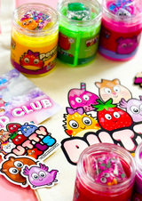 Close up of a tote bag with Putty Pals logo with three jars of coloured cloud putty and stickers on the bag.