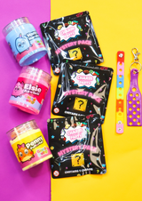 thee jars of colourful cloud putty in a line, three packs of mystery croc charms laid next to them also in a line and two colourful charm displays all on a yellow and purple background
