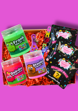 A box of three colourful jars of cloud putty with 3 packs of croc charm party bags on a purple background