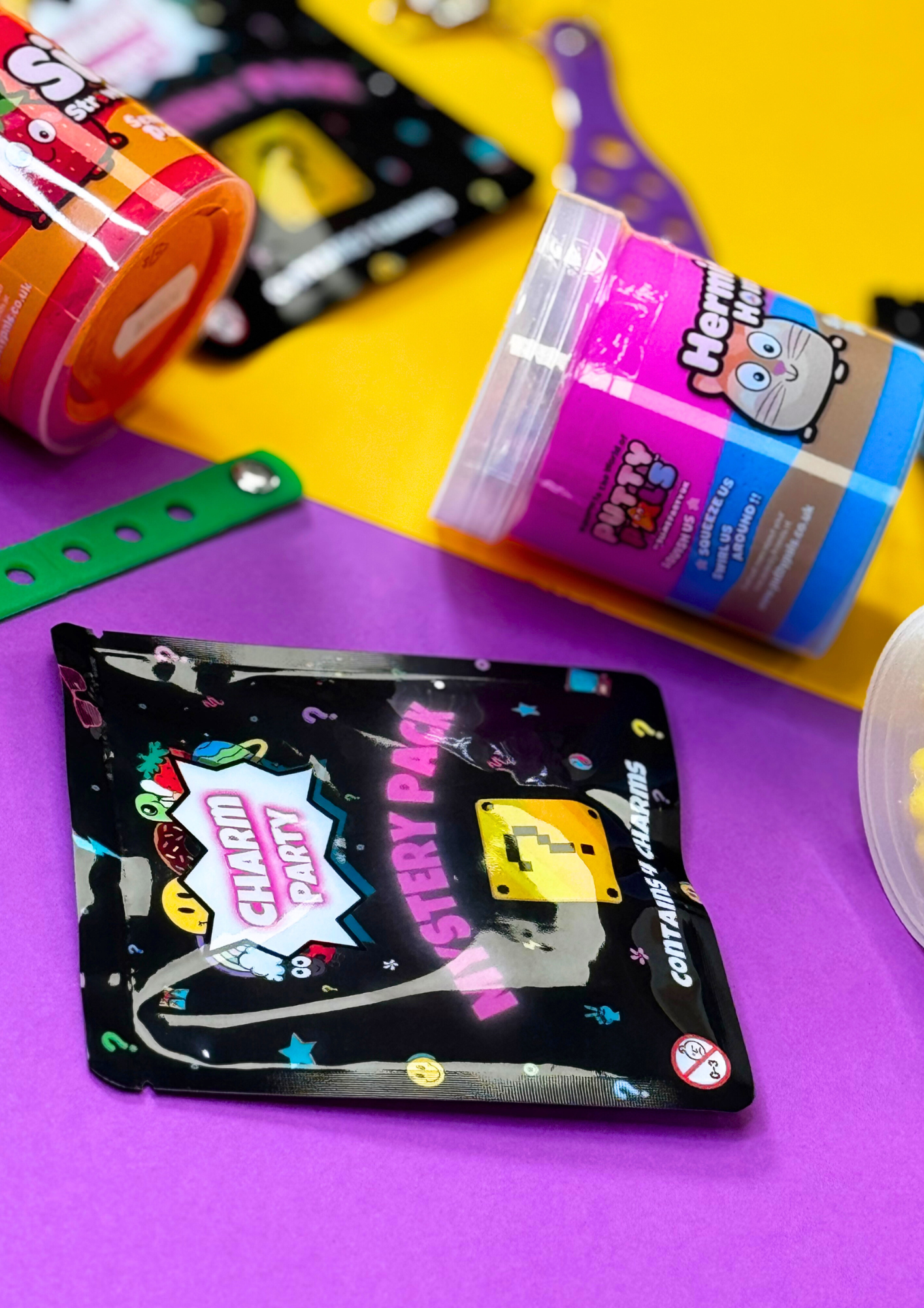 a close up of a colourful jar of sensory putty and a mystery pack of croc charms