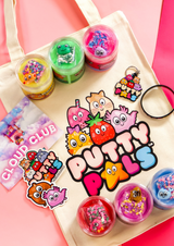 Six jars of colourful cloud putty on a tote bag with the Putty Pals logo on it. Character stickers, keyring and a bracelet are all laid on the bag.