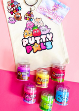 A tote bag with the Putty Pals logo on with colourful jars of could putty at the bottom, stickers and a keyring are also laid on the bag. 
