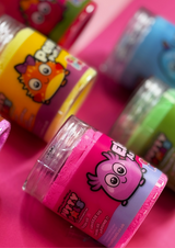 Close up of a pink jar of cloud putty with several other jars of different coloured putty blurred in the background.