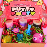 A pink box filled with 3 jars of sensory putty, a spiky ball, a sqeezey llama and narwhal and 2 animal shaped sugar fidget toys