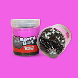 A jar of purple and black sensory putty called Barry Bat. A jar laid on the side showing black bingsu beads, clay sprinkles and a cartoon bat charm.