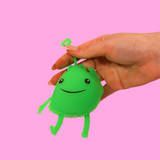 A hand holding the top of a green light up fidget toy that has arms and legs and a smiley face.