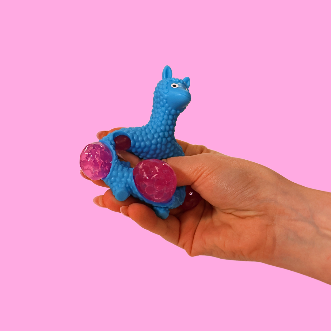 A blue orbs filled fidget toy in the shape of a llama, being squeezed in a hand against a pink background