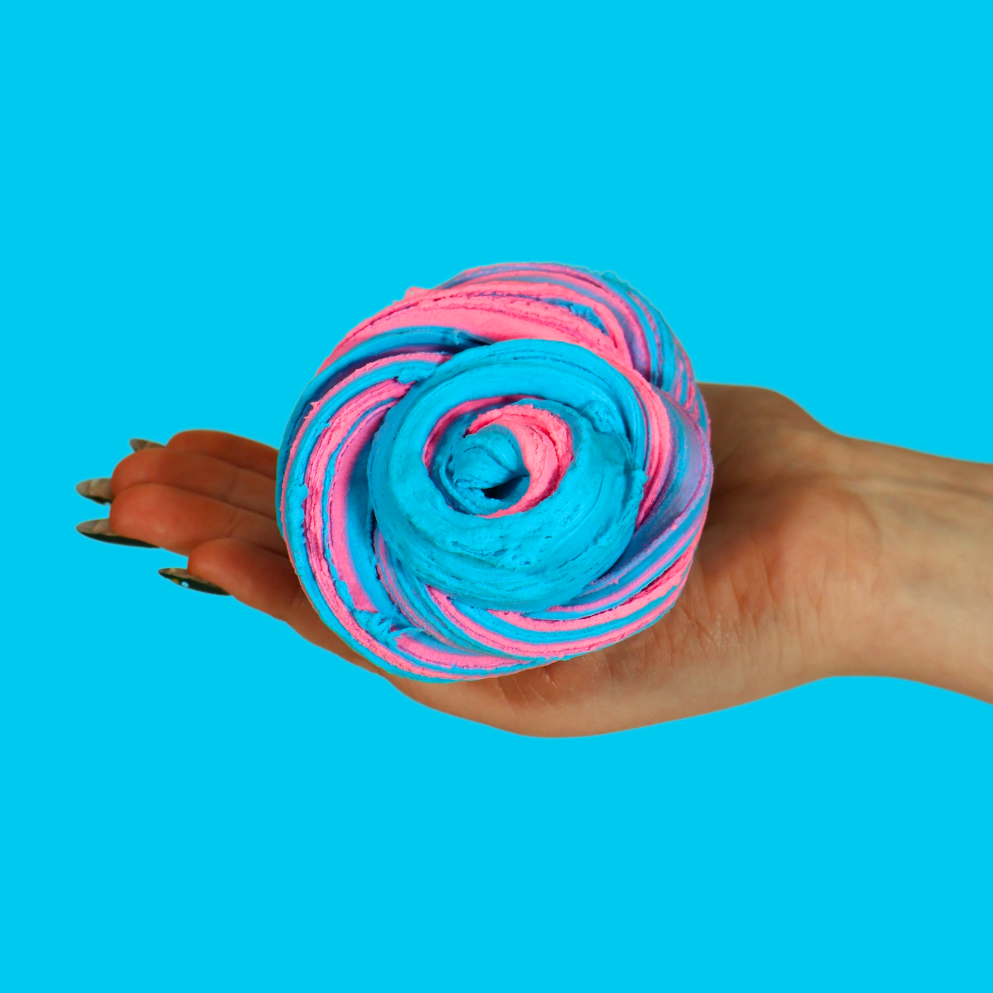 A swirl of mixed pink and blue sensory putty held in a hand against a blue background