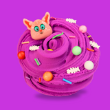 A purple swirled sensory putty decorated with multi coloured, clay sprinkles, floam balls, with clay fish bones. A cartoon sphynx cat charm is on the top left smiling