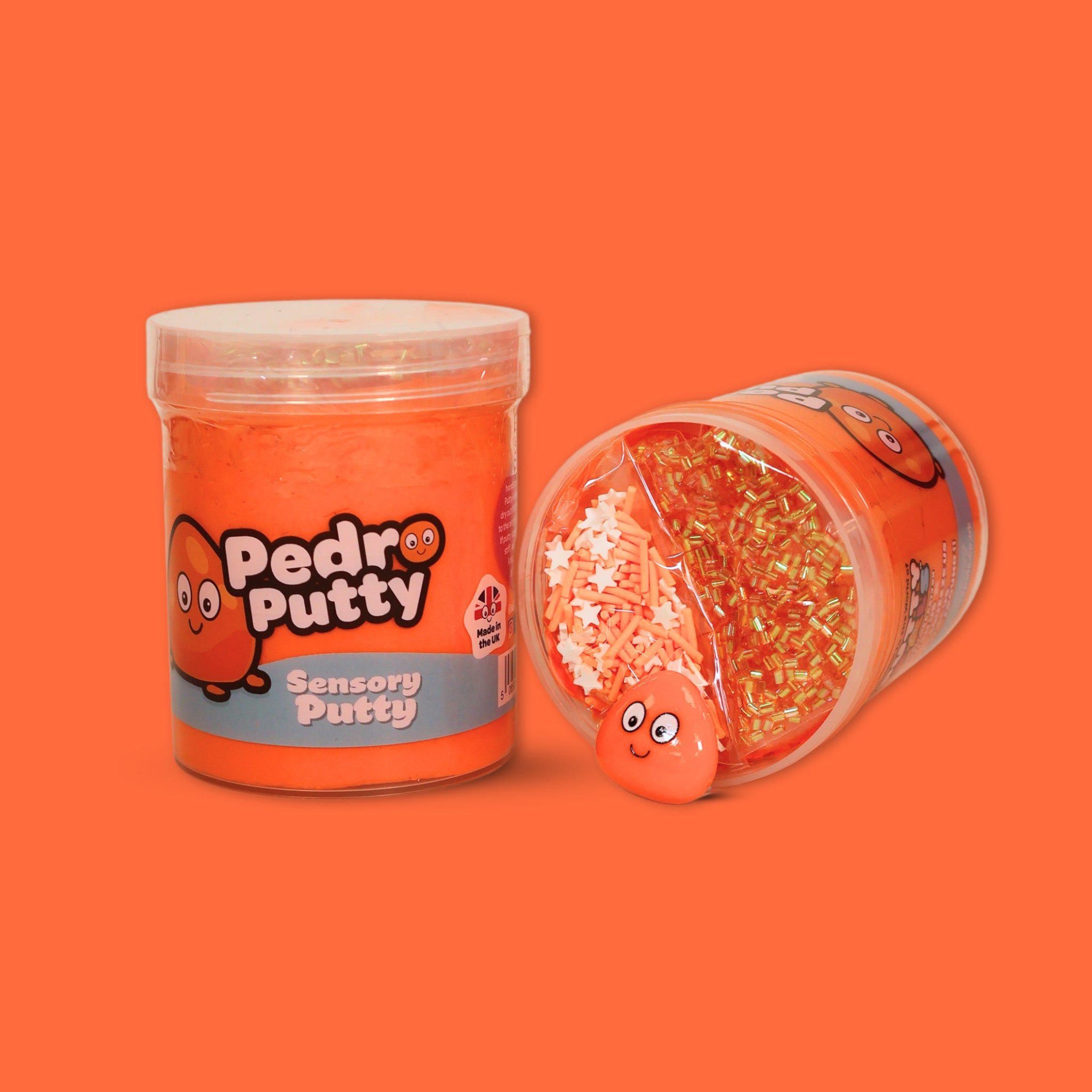 A jar of orange sensory putty called Pedro Putty, a jar laid on its side showing orange bingsu beads, clay sprinkles and an orange cartoon charm