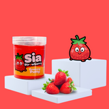 Red sensory putty on a plinth, collectable charm Sia Stawberry to the side, with some strawberries showcasing the scent on the bottom