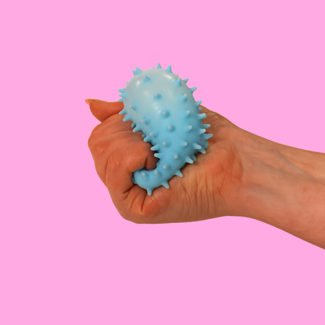 A blue fidget triangle being squashed in a hand against a pink background