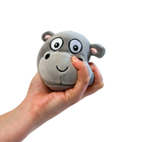 White background with a hand coming in from the side squishing a hippo plush sugar ball with a smiley face